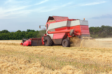 Fototapeta premium Wheat harvesting on field in summer season. Combine harvester harvests ripe wheat. agriculture. Process of gathering crop by agricultural machinery.