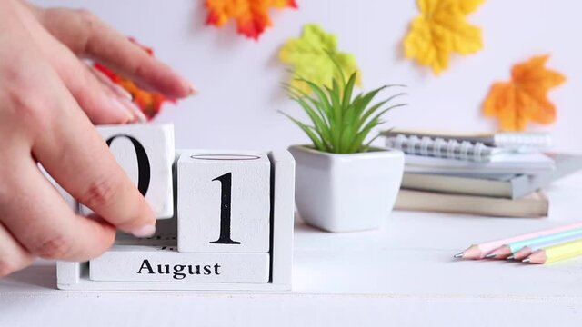 Back to school concept. Female hands flip through the calendar from August 31 to September 1 on the desktop. Hello autumn