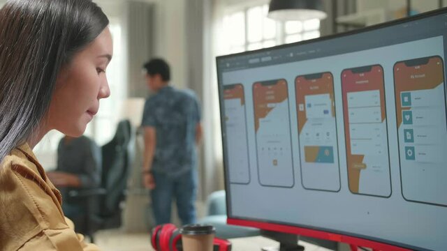 Asian Female Mobile Application Developer Works With Graphics On Her Personal Computer In Office
