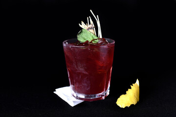 refreshing alcoholic drink with berries, ice vodka and gin, lemon peel served in glass cup on the counter on black background