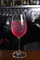 refreshing alcoholic drink with berries, ice vodka and gin, lemon peel served in glass cup on the counter on blurred background