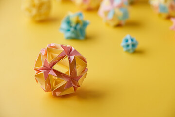 Set of multicolor handmade modular origami balls or Kusudama Isolated on yellow background. Visual...
