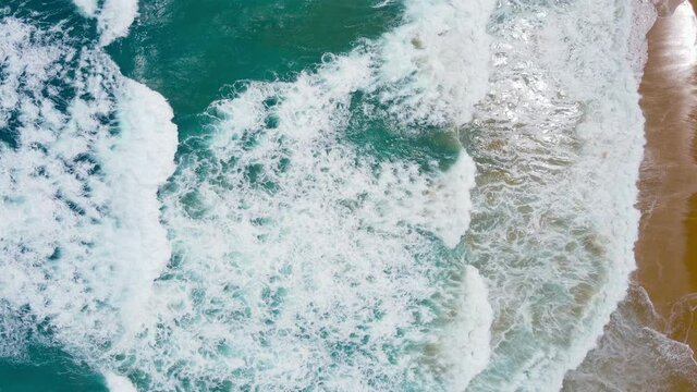 Top-down drone view shot. on the Andaman coast. Beautiful nature seawater wave texture. The sea and large ripples that wash against the shore are filled with beautiful soft white sponges.