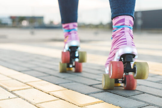 Young woman legs riding on colorful roller-skates. Back bottom view
