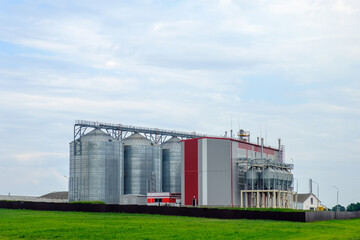 Fototapeta na wymiar Agribusiness concept. Agro-processing and manufacturing plant with metal silos for grain storage, drying, cleaning agricultural products, flour, cereals and grain