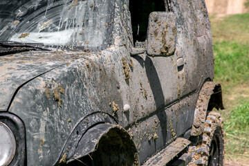 a muddy car in a swamp layer after an off-road trip, a close-up of a side driver door with rear view mirror and sills on fender for expedition conditions.
