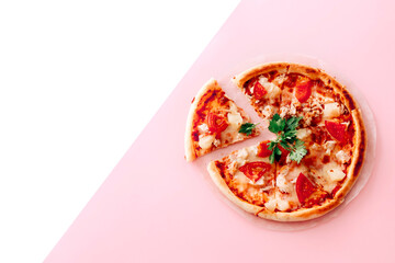 Top view with a sliced pizza on white and pink background.