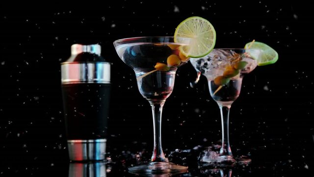 Animation of specks moving over cocktail glasses with olives and ice on black background