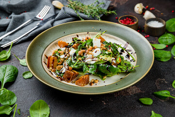 salad with pumpkin, cheese and herbs, cashews on grey plate on dark concrete table