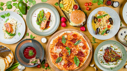 Fototapeta na wymiar Italian meat pizza, salmon steak with avocado, spaghetti with shrimps and mussels, burger with meat, pork reabs bbq, borsht, bread, spaghetti with salmon top view on wooden table
