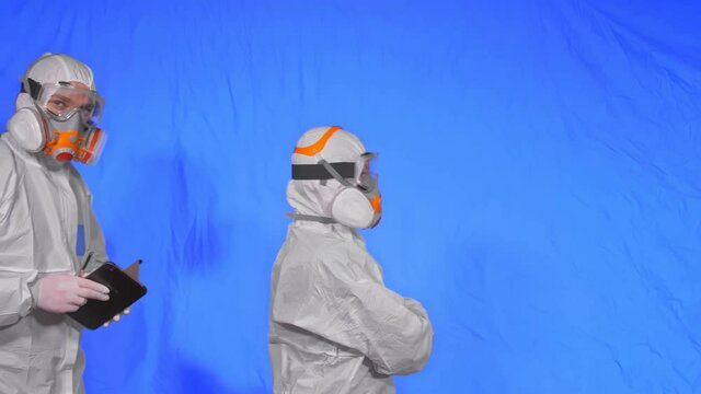 Scientist virologist in respirator makes write in an tablet computer with stylus. Man and woman wearing protective medical mask. Health safety virus coronavirus epidemic 2019 nCoV. Chroma key blue.