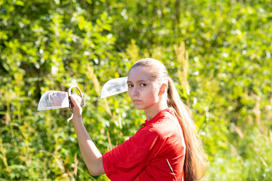 Close up portrait  . A 
beautiful teen girl sportswoman athlete engaged in Wushu outside, in red sport kung fu costume, training  with traditional wing chun sport knives butterflies