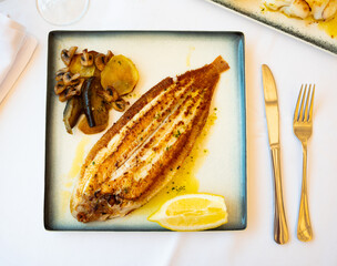 Delicious roasted black sole fish served with stewed vegetables and fresh lemon seasoned with...