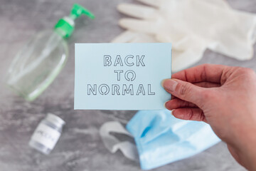 covid-19 vaccine race, Back to Normal message with Vaccine ampoule next to disposable gloves, hand sanitizer and face mask in the background