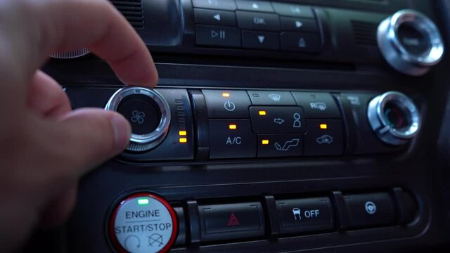 Turning off air conditioning and starting heating. A mans hand presses the button in the car. 4K video footage.