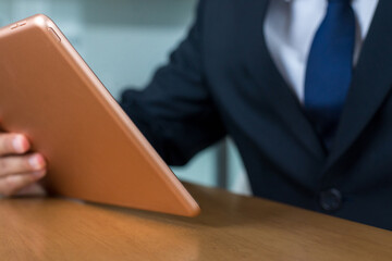 Businessman in suit working on social media strategy and using a digital tablet while sitting in office.