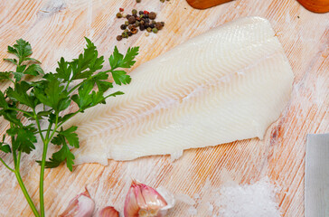 Raw Atlantic halibut fillet on wooden table with condiments. Seafood delicacy - obrazy, fototapety, plakaty