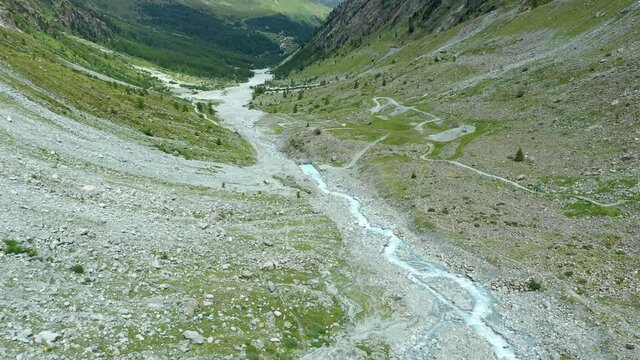 Drone flight over a winding glacier river through a high mountain alpine valley.