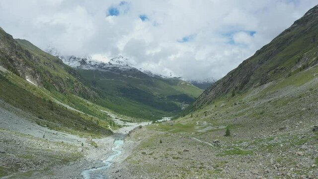 Drone flight over a winding glacier river through a high mountain alpine valley.