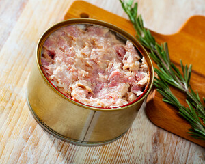 Closeup view of open tin can of stewed meat on wooden table