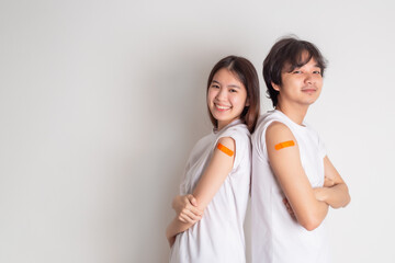 Young Asian couple showing thumb up gesture and shows off an orange bandage after receiving the...