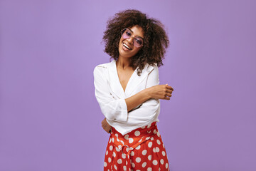 Charming lady in white blouse and glasses smiling on isolated background. Wavy haired woman in...