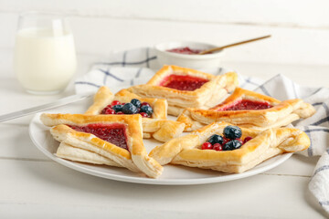 Plate with danish pastry on white wooden background