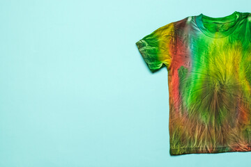 Half of a tie dye-style T-shirt on a light blue background. Space for the text. Flat lay.