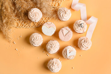 Tasty cupcakes and wedding rings on color background