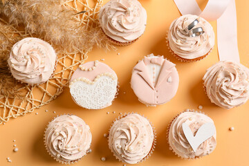 Tasty cupcakes and wedding rings on color background