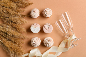 Tasty wedding cupcakes and glasses on color background