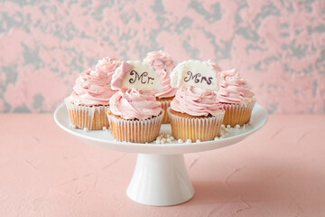 Dessert stand with tasty wedding cupcakes on table