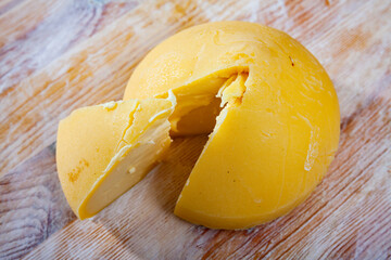 Cone-shaped head of traditional Galician Tetilla cheese with cut slice on wooden background