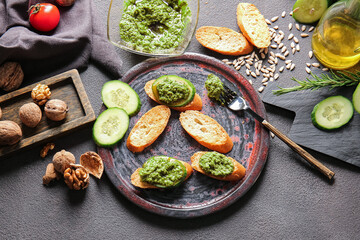 Composition with tasty pesto sauce and toasts on dark background
