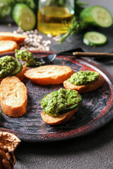 Tasty toasts with pesto sauce on dark background, closeup