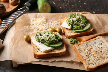 Tasty toasts with pesto sauce on dark background, closeup
