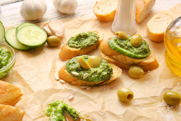 Tasty toasts with pesto sauce and olives on table, closeup