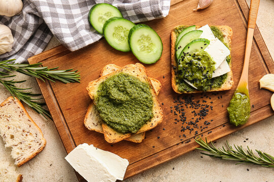 Tasty toasts with pesto sauce on color background