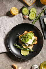 Tasty toast with pesto sauce and lime on grunge background