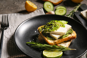 Tasty toast with pesto sauce and lime on table, closeup