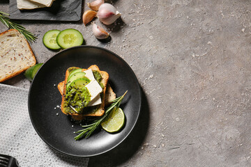 Tasty toast with pesto sauce and lime on grunge background