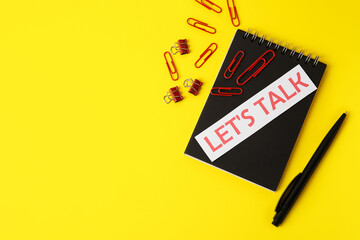 Text LET'S TALK with notebook and clips on color background