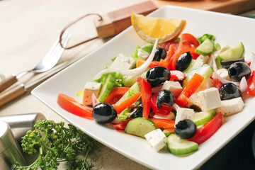 Plate with tasty Greek salad on table, closeup