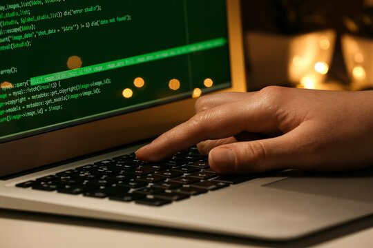 Female programmer working with laptop in office at night, closeup