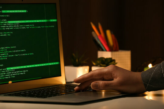 Female programmer working with laptop in office at night, closeup