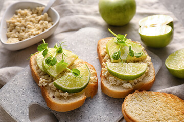 Tasty bruschettas with apple, lime and hummus on grunge background, closeup