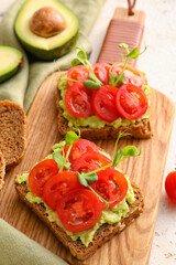 Tasty bruschettas with tomato and guacamole on light background, closeup