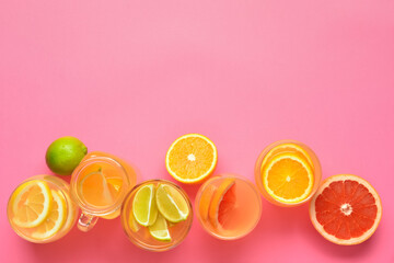 Glasses of lemonade with citrus fruits on color background