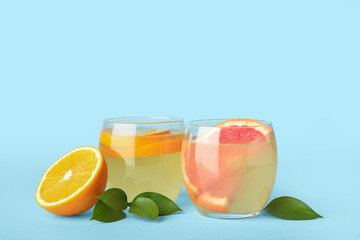 Glasses of citrus lemonade on color background