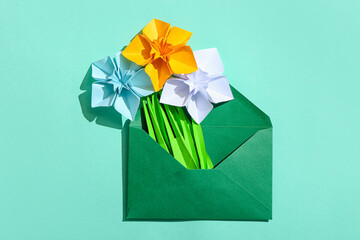 Origami daffodils and envelope on color background
